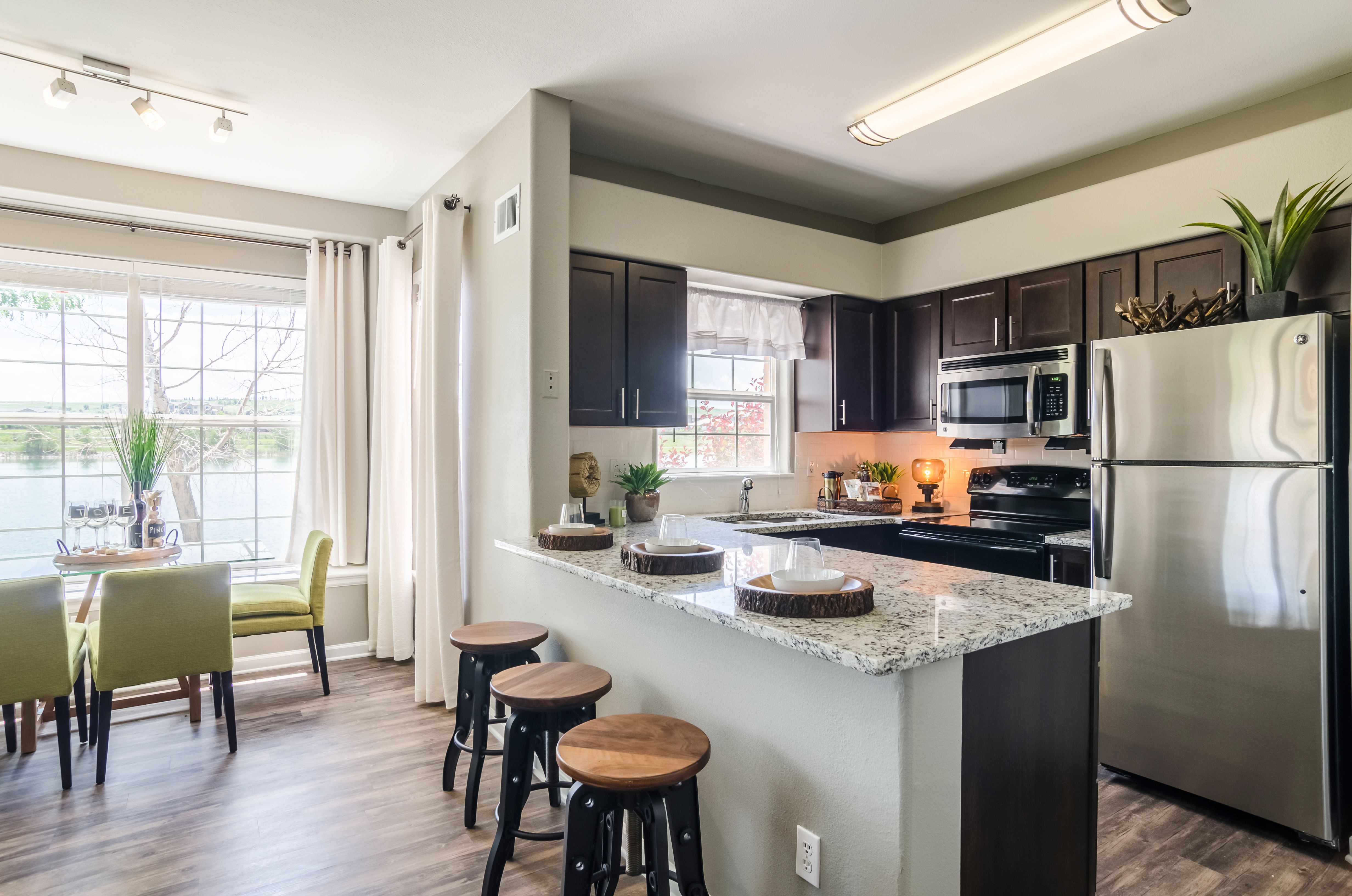 A kitchen with a refrigerator, stove, and bar stools.